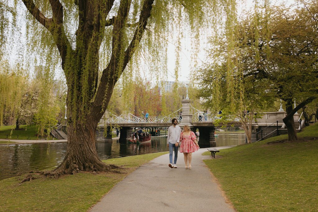 A couple during their engagement session in the Boston Public Garden in front of Lagoon Bridge