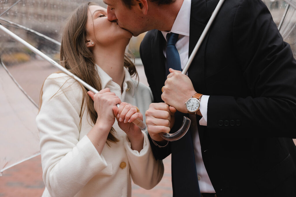 Quintessential Boston City Hall elopement - Couple kisses under umbrellas